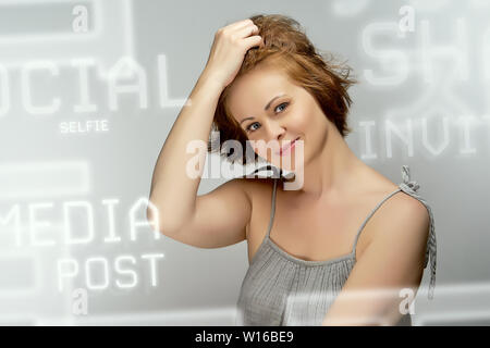 Bella attraente i capelli rossi donna pone in studio su sfondo grigio. Foto Stock