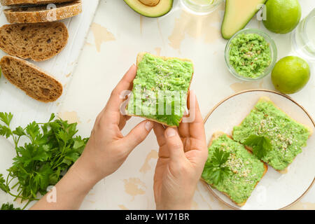 Donna di mangiare gustoso avocado toast a tavola Foto Stock