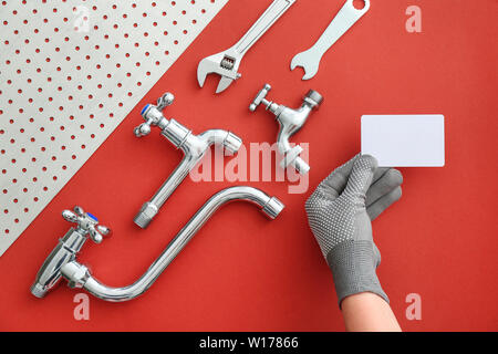 Mano di idraulico con business card e gli elementi sul colore di sfondo Foto Stock