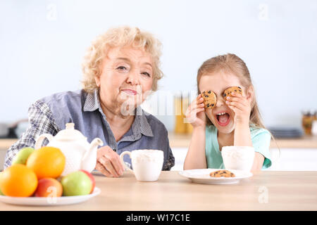 Carino bambina e la nonna bere il tè con biscotti in cucina Foto Stock