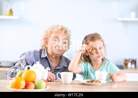 Carino bambina e la nonna bere il tè con biscotti in cucina Foto Stock