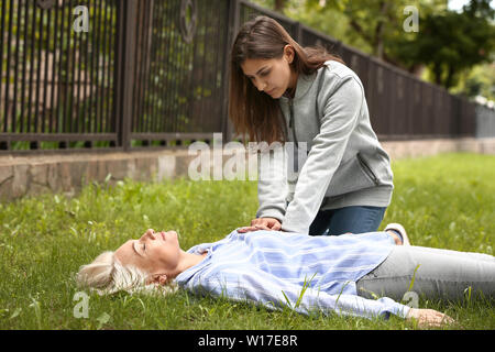 Passer femmina-eseguendo la RCP su inconscio donna matura all'aperto Foto Stock