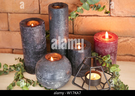 Candele accese e rami di eucalipto sul ripiano vicino alla parete del colore Foto Stock