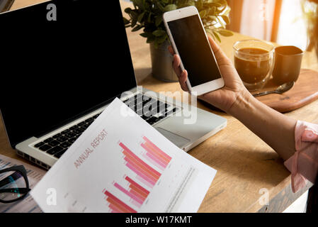 Vista superiore della giovane donna di lavoro utilizzando laptop e la lettura della relazione , grafici , grafici, documento al lavoro. Business donna lavora alla sua scrivania. Foto Stock