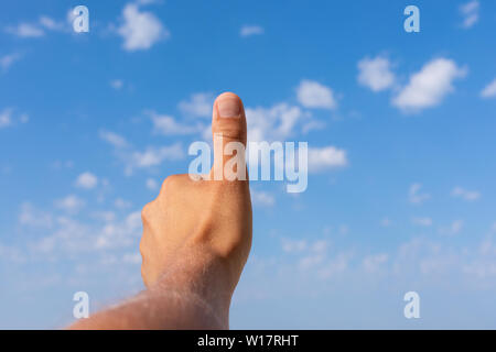 Immagine di un giovane di mano mostra Thumbs up con nuvoloso cielo blu in background Foto Stock