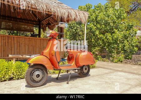 Rosso di vecchio stile moto scooter - tradizionale indonesiano titolo di trasporto su un'isola tropicale. Orange vintage Vespa scooter sprint. Traditio Foto Stock