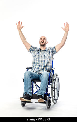 Uomo caucasico espressione sorridente e braccia tese verso il cielo, disabili su sedia a rotelle su sfondo bianco. Foto Stock