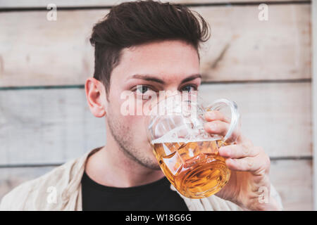 Ritratto di giovane millenaria maschio adulto di bere un bicchiere di birra per esterno Foto Stock