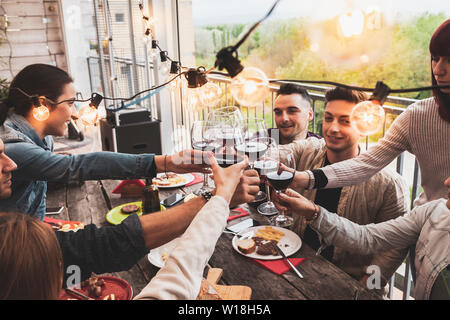 Felice gruppo di amici bevendo vino rosso e mangiare la pizza al bar birreria ristorante. concetto con i giovani avendo divertimento genuino Foto Stock