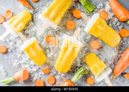 Gelato vegetale. Carota Vegan gelato popsicles con organici carotine, vecchio rustico sfondo di legno. Foto Stock