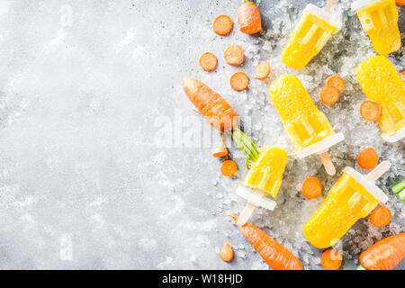Gelato vegetale. Carota Vegan gelato popsicles con organici carotine, vecchio rustico sfondo di legno. Foto Stock