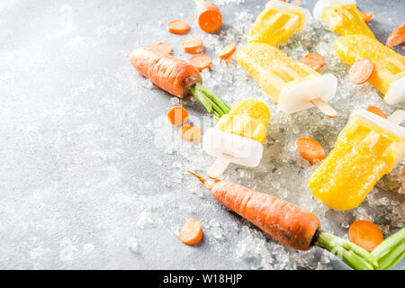 Gelato vegetale. Carota Vegan gelato popsicles con organici carotine, vecchio rustico sfondo di legno. Foto Stock