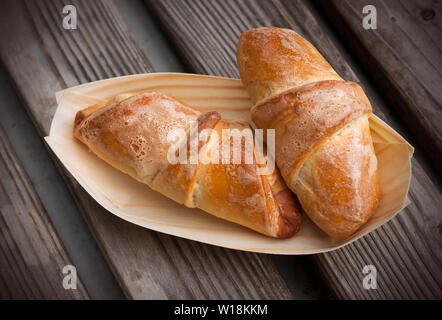 Cornetti fatti in casa in un piatto bio, sullo sfondo di legno. Due cornetti con cherry Foto Stock