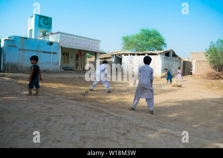 Rahimyar khan,punjab,pakistan-luglio 1,2019:alcuni ragazzi locali a giocare a cricket in un villaggio,battitore giocando un colpo,polvere battenti. Foto Stock