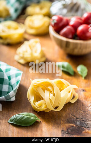 La pasta italiana Le tagliatelle su tavola con basilico e pomodori Foto Stock