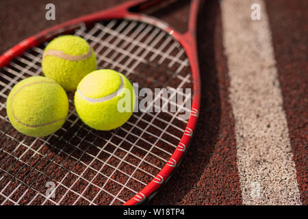 Tre campi da tennis giallo sfere giacente sulla racchetta da linea bianca sul stadium parco giochi Foto Stock