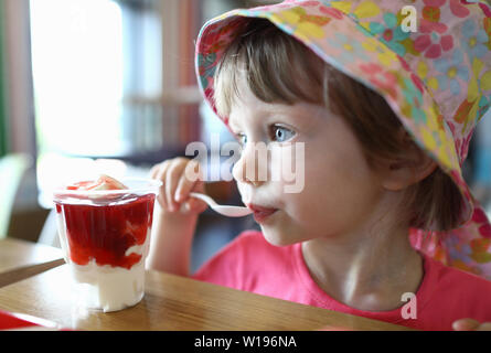 Soddisfatto piccolo bambino cucchiaio lecca con ghiaccio Foto Stock