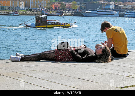 Due giovani sul fiume Douro quayside donna a prendere il sole nel marzo 2019 Ribeira Porto Oporto portogallo Europa KATHY DEWITT Foto Stock