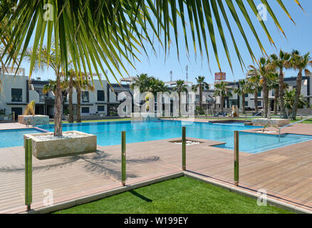 Torrevieja, Spagna - 1 Maggio 2019: vista la nuova costruzione moderna cittadina case chiuse urbanizzazione con piscina palme, lussuoso edificio residenziale Foto Stock
