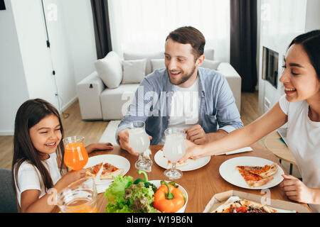 Famiglia Pizza godendo il pranzo. Bambina divertendosi con la sua famiglia Foto Stock