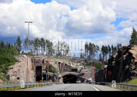 Superstrada paesaggio di E18 nel sud della Finlandia con tunnel avanti con il traffico lento e cielo blu e nuvole bianche. Foto Stock