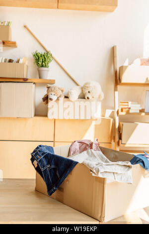 Cabinet in legno e scatole di cartone con abiti, libri e giocattoli in centro di carità Foto Stock