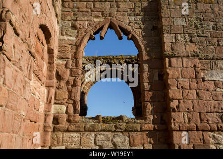 Il rovinato le mura del monastero di Lindisfarne Priory sull Isola Santa il 27 giugno 2019, sull isola di Lindisfarne, Northumberland, Inghilterra. Il monastero di Lindisfarne fu fondata dal monaco irlandese San Aidan e il priorato fu fondata prima della fine dell'634 e Aidan vi rimase fino alla sua morte nel 651. Il Santo Isola di Lindisfarne, nota anche semplicemente come Isola Santa è un'isola di fronte alla costa nord-est dell'Inghilterra. A Isola Santa ha una storia registrata a partire dal VI secolo D.C. fu un importante centro di cultura celtica e Anglo-sassone il cristianesimo. Dopo le invasioni dei Vichinghi e la conquista normanna di Englan Foto Stock