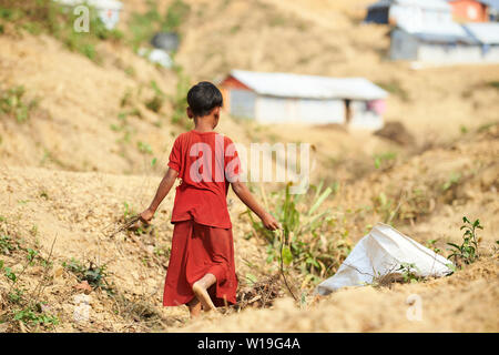 Bambino in abito rosso la raccolta di legna da ardere in Rohingya Refugee Camp Kutupalong, Bangladesh Foto Stock