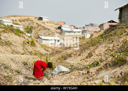 Bambino in abito rosso la raccolta di legna da ardere in Rohingya Refugee Camp Kutupalong, Bangladesh Foto Stock