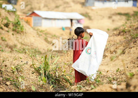 Bambino in abito rosso la raccolta di legna da ardere in Rohingya Refugee Camp Kutupalong, Bangladesh Foto Stock