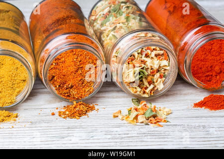 Spezie travaso dei vasetti giacente su un bancone di legno. liofilizzata verdure, Paprica macinata, curry e miscele di spezie. Foto Stock