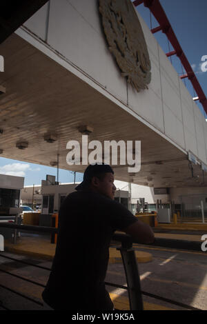 Matamoros, Messico. Il 30 giugno, 2019. Un giovane America centrale sembra migranti sotto la Puerta Messico ponte verso gli Stati Uniti, il gateway per il suo paese confinante. Centinaia di migranti sono in attesa nei pressi del ponte internazionale per chiedere asilo negli Stati Uniti. L'atmosfera è disperata come molti migranti vivere all'aperto in mezzo alle alte temperature che prevalgono nella Comunità sul Messico settentrionale, al confine. Credito: Carlos Ogaz/dpa/Alamy Live News Foto Stock