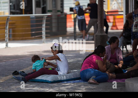 Matamoros, Messico. Il 30 giugno, 2019. Una ragazza si siede accanto al suo fratello più piccolo su un materasso gonfiabile vicino alla Puerta Messico Bridge. Centinaia di migranti sono in attesa nei pressi del ponte internazionale per chiedere asilo negli Stati Uniti. L'atmosfera è disperata come molti migranti vivere all'aperto in mezzo alle alte temperature che prevalgono nella Comunità sul Messico settentrionale, al confine. Credito: Carlos Ogaz/dpa/Alamy Live News Foto Stock