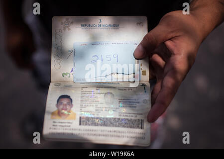 Matamoros, Messico. Il 30 giugno, 2019. Bryan mostra il suo passaporto, che accredita lui come un cittadino nicaraguense, accanto al numero dato a lui da noi le autorità di immigrazione per la domanda di asilo in quel paese. Centinaia di migranti sono in attesa vicino alla Puerta internazionale Ponte del Messico per chiedere asilo negli Stati Uniti. L'atmosfera è disperata come molti migranti vivere all'aperto in mezzo alle alte temperature che prevalgono nella Comunità sul Messico settentrionale, al confine. Credito: Carlos Ogaz/dpa/Alamy Live News Foto Stock