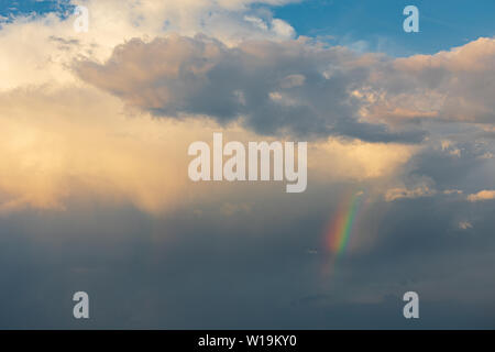 Piccolo arcobaleno dopo la pioggia alla luce del tramonto Foto Stock