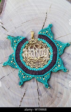 Ottone pendente in metallo con tecnica macrame Gioielleria Ciondolo su sfondo di legno Foto Stock