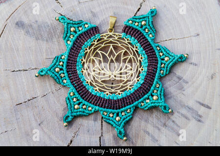 Ottone pendente in metallo con tecnica macrame Gioielleria Ciondolo su sfondo di legno Foto Stock