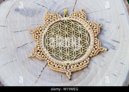 Ottone pendente in metallo con tecnica macrame Gioielleria Ciondolo su sfondo di legno Foto Stock