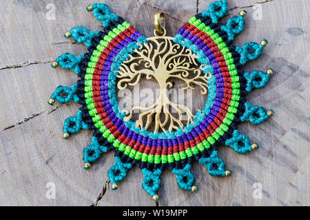 Ottone pendente in metallo con tecnica macrame Gioielleria Ciondolo su sfondo di legno Foto Stock