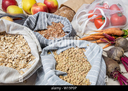 Negozi di generi alimentari in sacchetti riutilizzabili su lino naturale o la canapa sfondo. Concetto di rifiuti zero shopping etico: raw vegan alimenti compresi ortofrutticoli, ri Foto Stock