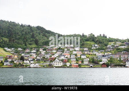 Linea di case collina dall'acqua dell'Hardangerfjord in Norheimsund, Hordaland County, Norvegia. Foto Stock