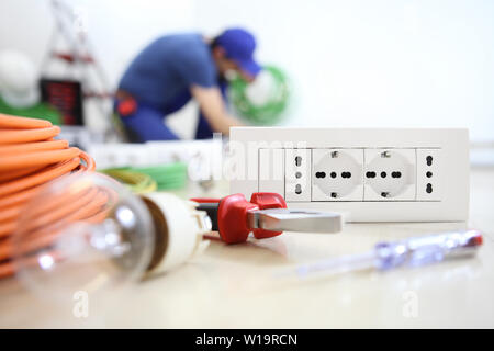 Elettricista e lavorare con le apparecchiature elettriche in primo piano, lampadina, strumenti e socket, circuiti elettrici, cablaggio elettrico Foto Stock