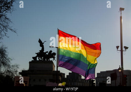 Una bandiera arcobaleno con 'pace scendendo sul carro di guerra", una statua sulla sommità del Wellington Arch vicino a Hyde Park Corner nel centro di Londra. Un palo coperto con le telecamere TVCC è nelle vicinanze. Foto Stock