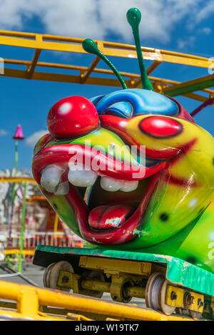 Un colorato fumetto fiera rollercoaster carrello sulle rotaie in un luna park nel sud dell'Inghilterra. Foto Stock