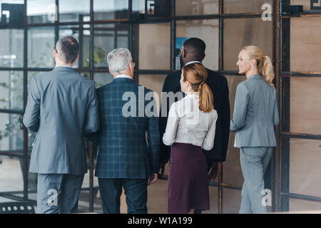 Vista posteriore di uomini di affari multiculturali e imprenditrici a piedi in ufficio Foto Stock