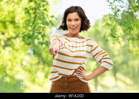 Felice donna sorridente puntare il dito a voi Foto Stock