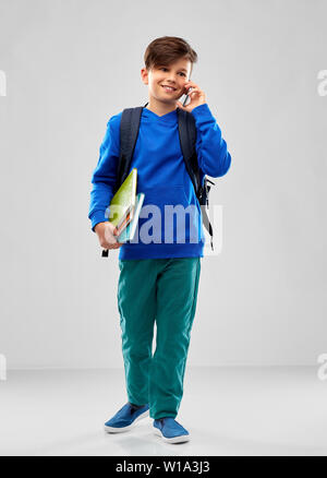 Studente ragazzo con borsa scuola chiamando sullo smartphone Foto Stock