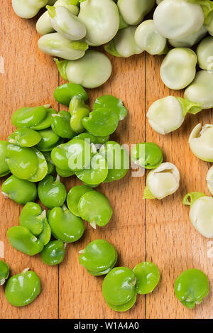 Sbucciate e Nazioni Unite Sbucciate le fave su un tagliere di legno Foto Stock