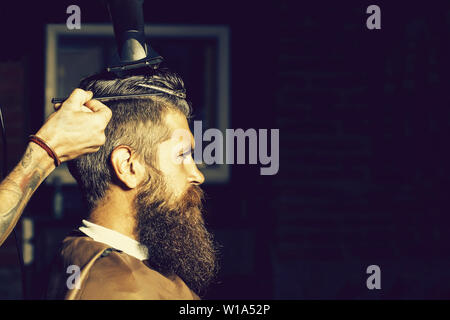 Uomo Barbuto getting hair styling da parrucchiere a barberia Foto Stock