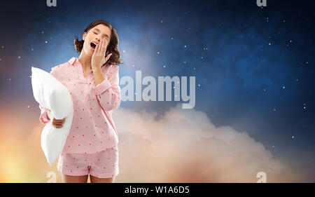 Assonnato sbadigli giovane donna in pigiama con cuscino Foto Stock